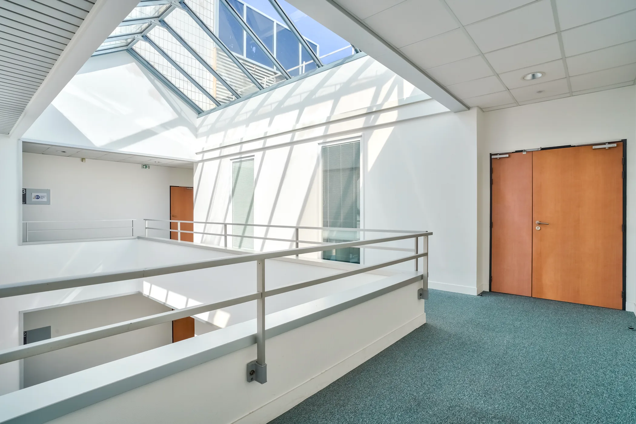 Couloir d’un bâtiment professionnel donnant sur des bureaux et salles de réunion