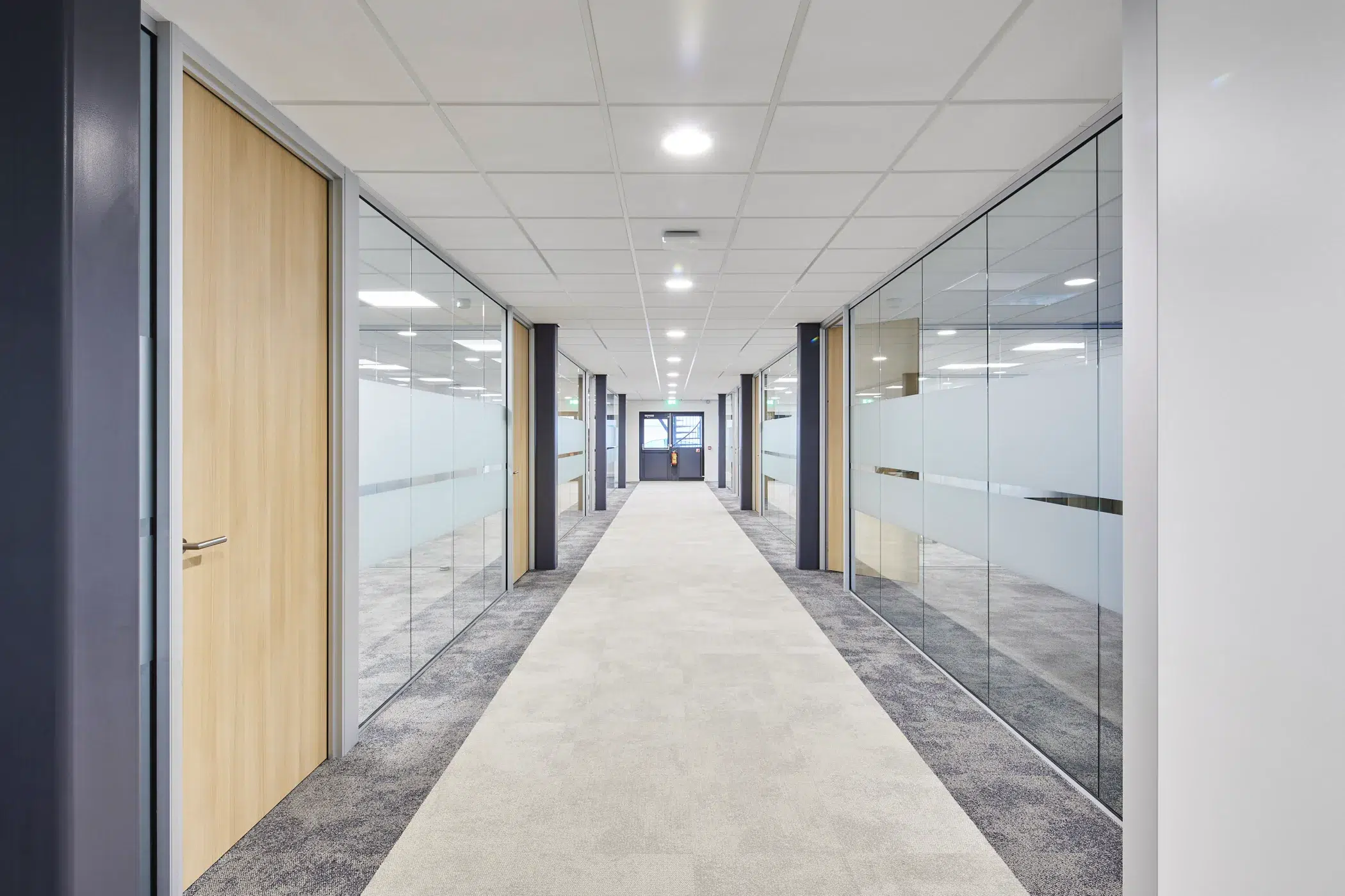 Couloir avec bureaux fermés et vitrés dans un immeuble professionnel