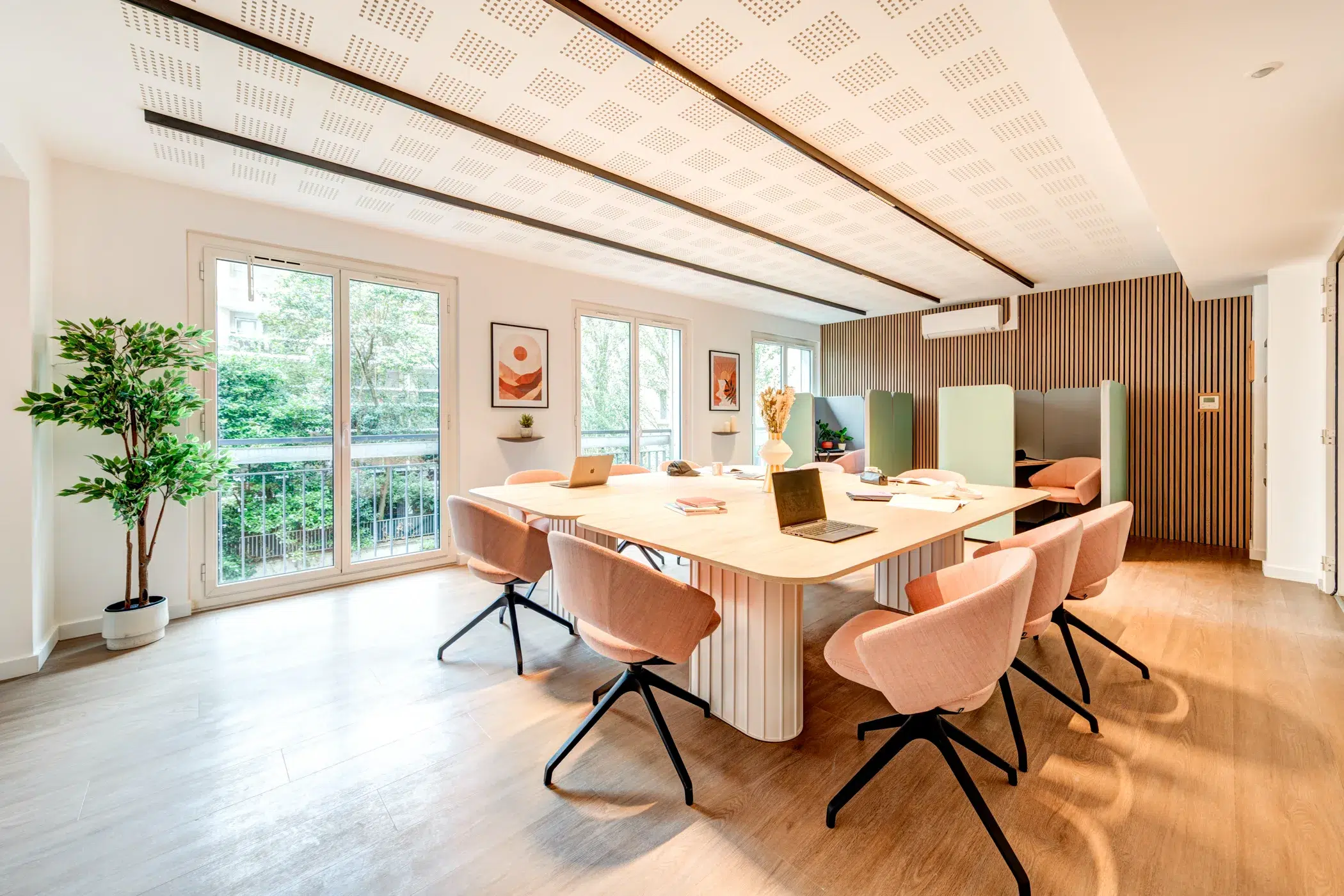 Open space avec grande table centrale, chaises et espaces de travail ouverts