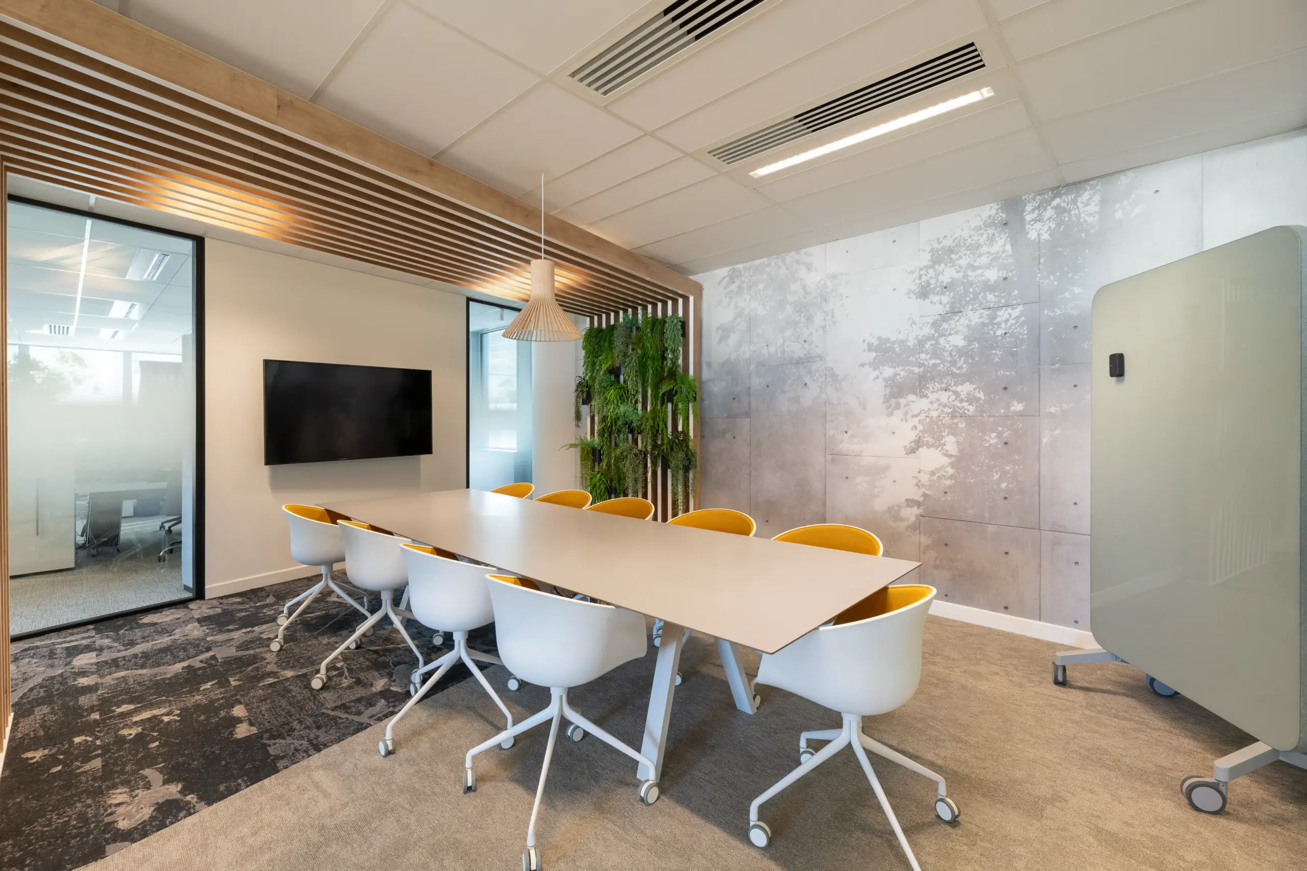 Petite salle de réunion avec table centrale, chaises et écran dans un bâtiment professionnel